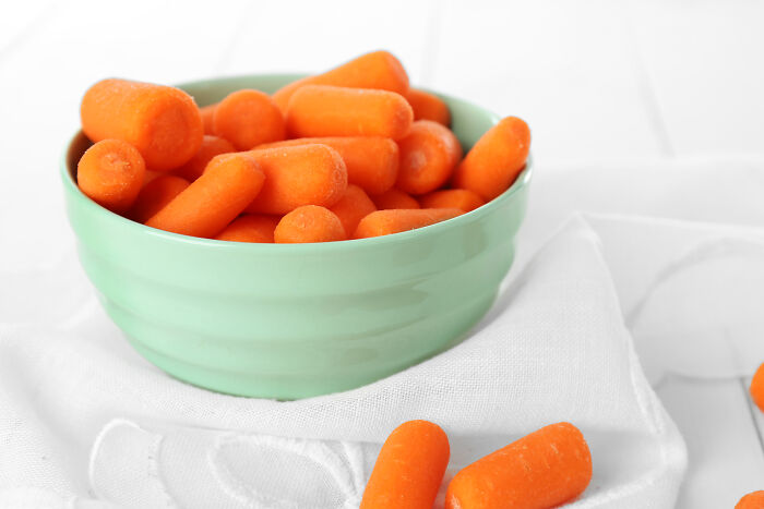 Bowl of fresh baby carrots on a white cloth, highlighting healthy snack choices and things learned embarrassingly late.