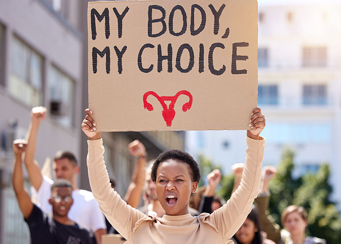 Protester holding a My Body My Choice sign amid a crowd, expressing modern behaviors they can't accept growing up.