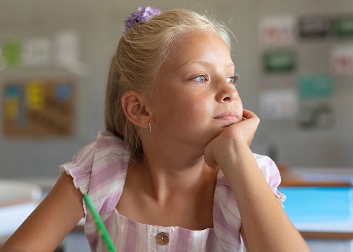 Young girl looking thoughtfully out of window reflecting on modern behaviors she struggles to accept due to how she grew up