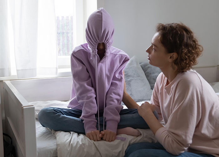 Two people in a bedroom showing modern behaviors and struggles shaped by how they grew up, reflecting emotional tension.