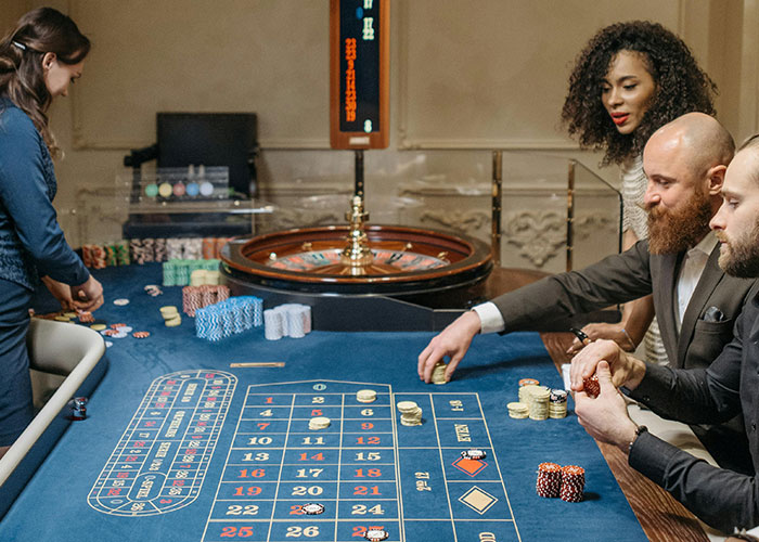 Three people playing roulette at a casino table, illustrating modern behaviors some find hard to accept.