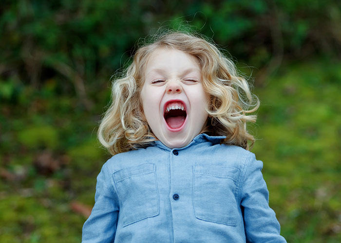 Young child with curly blonde hair wearing a blue shirt, expressing frustration about modern behaviors they can’t accept.