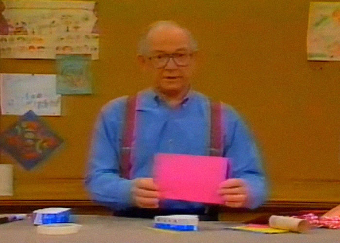 Older man in suspenders holding a pink paper, illustrating modern behaviors some people cannot accept from their upbringing.
