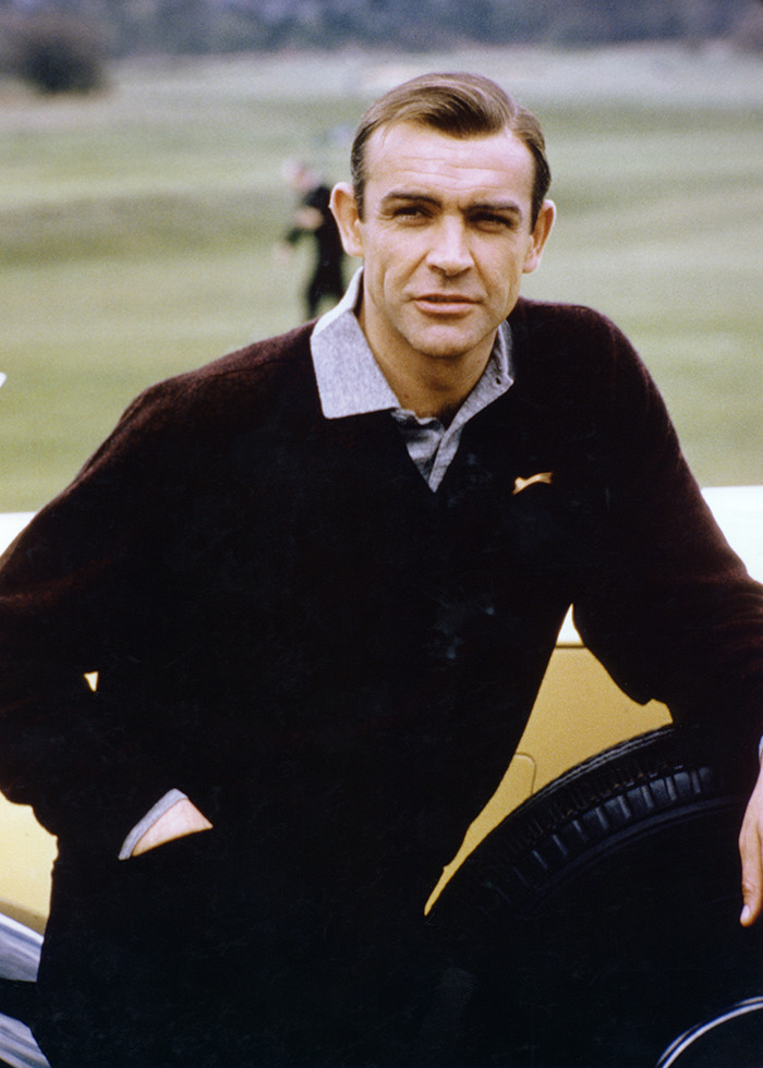 Sean Connery in a dark sweater leaning on a tire outdoors, highlighting James Bond actor viral photos debate.