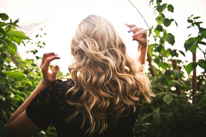 Woman with long wavy hair surrounded by greenery, illustrating themes of postpartum OCD and shared experiences among women.
