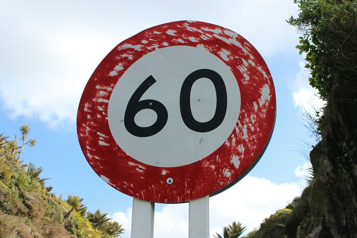 Worn speed limit sign with number 60 against a partly cloudy sky, illustrating famous paradoxes that confuse many.