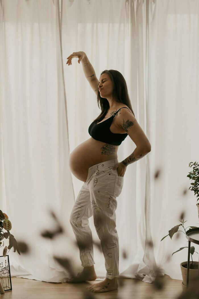 Pregnant woman posing indoors with artistic tattoos, illustrating moments people realized their close friend was a total jerk.