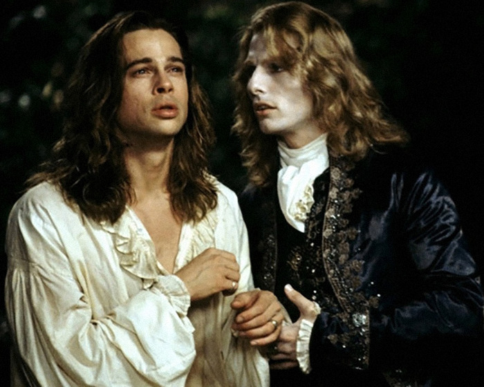 Two men dressed in vintage costumes engaged in an intense conversation under dim lighting.