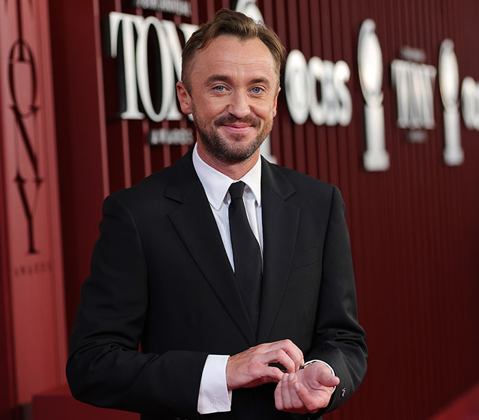 Tom Felton on the red carpet wearing a black suit, sparking Harry Potter fans' reactions with comments on J.K. Rowling.