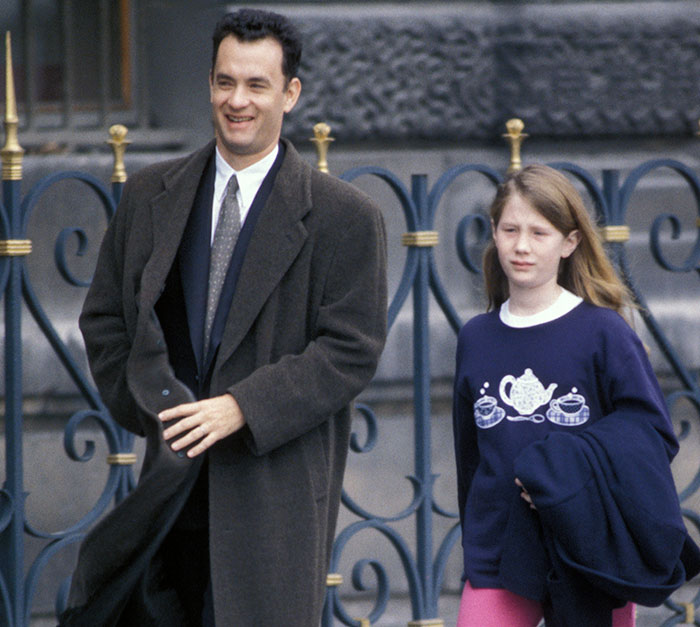 Tom Hanks walking outdoors with daughter, reflecting on childhood confusion, violence, and deprivation revelations.