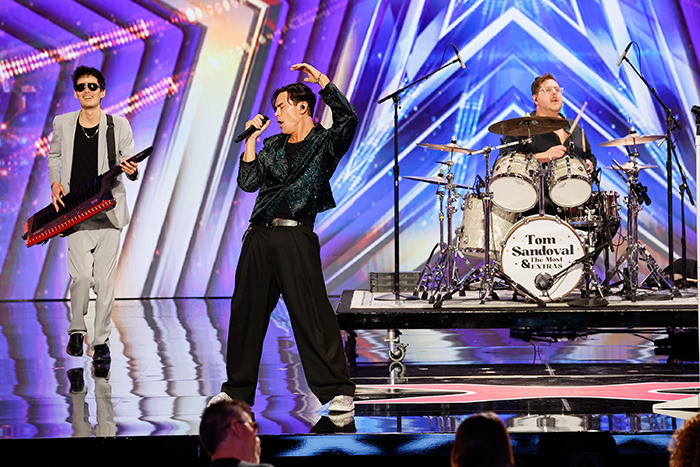 Tom Sandoval performing on stage during America&rsquo;s Got Talent audition with band members playing keyboard and drums.