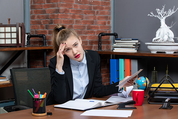 Frustrated woman stressed at desk illustrating mom expecting endless babysitting from sister instead of taking a trip. Frustrated woman stressed at desk illustrating mom expecting endless babysitting from sister instead of taking a trip.