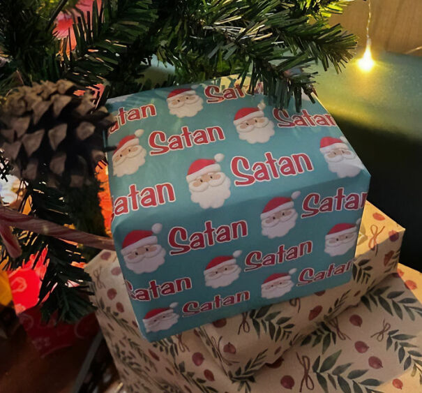 Gift wrapped in humorous English-themed paper with Santa faces and the word Satan, showcasing funny and baffling language use.