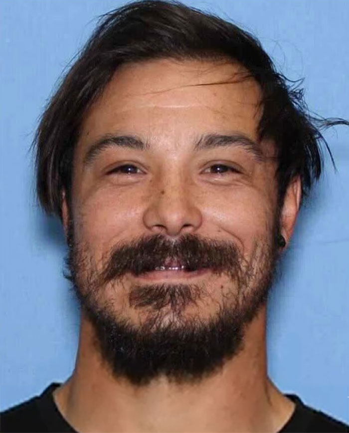 Man with dark hair and beard smiling against a blue background, related to tragic cause of passing for 3 sisters after visitation.
