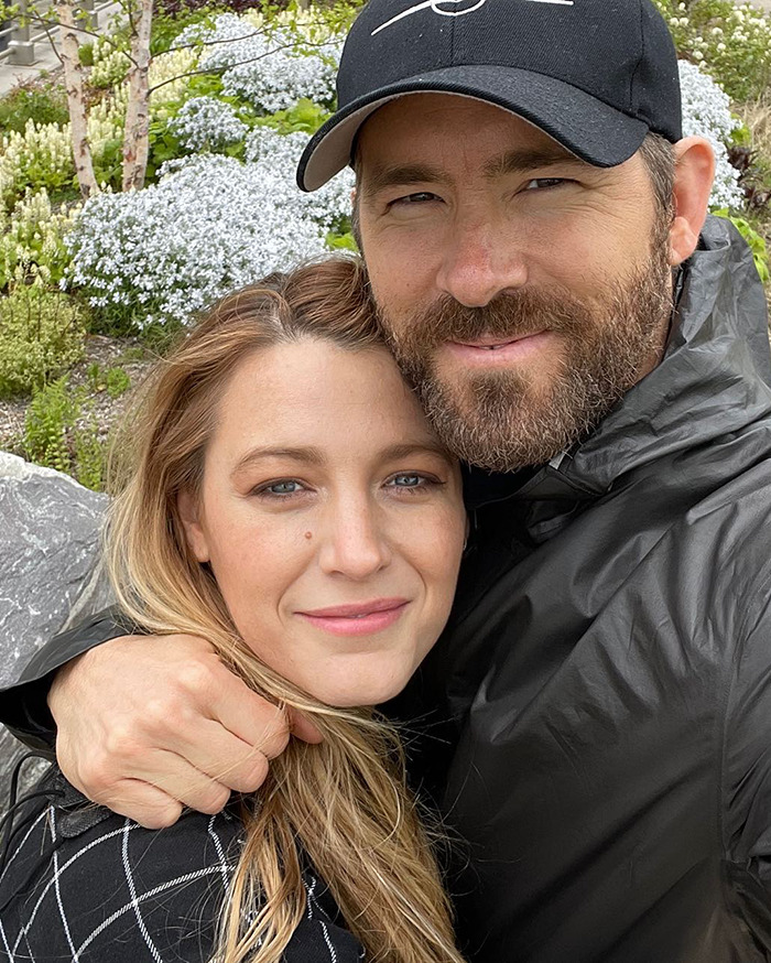 Blake Lively outdoors with a man, wearing casual clothes, amid greenery and flowers during a shopping trip controversy.