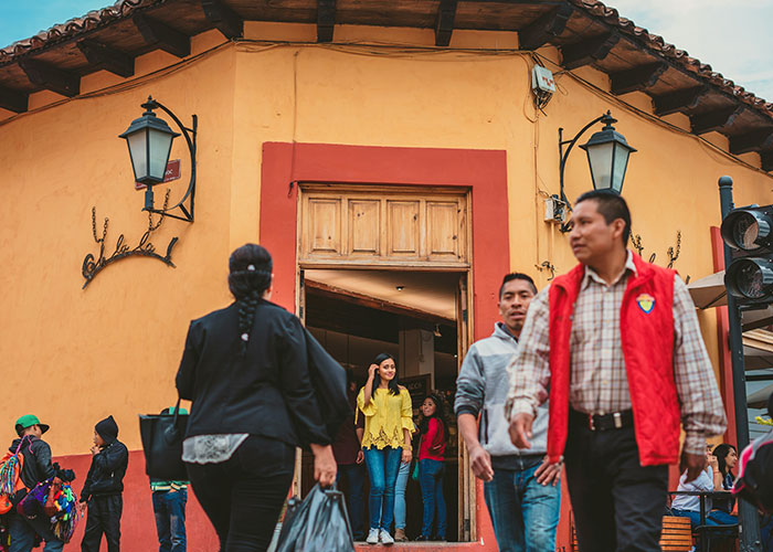 People share their most unbelievable experiences while walking outside a colorful building in a busy street scene.