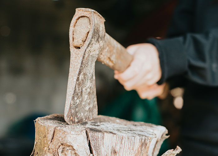 Person holding a rusty axe chopping wood, illustrating people sharing their most unbelievable experiences they can prove.