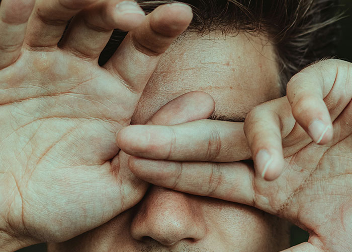 Person covering their eyes with hands, symbolizing people sharing their most unbelievable experiences they can prove.