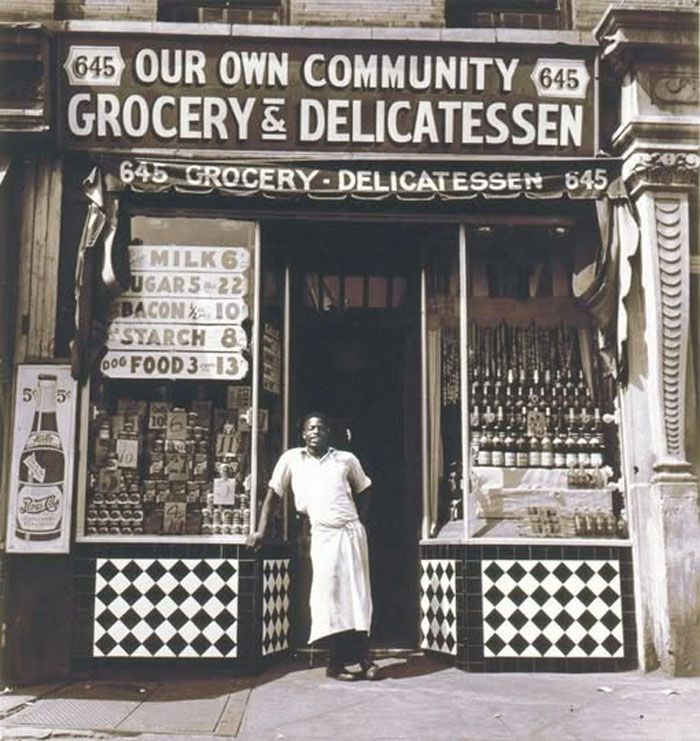Rare historical photo of a man standing outside a grocery and delicatessen storefront from the early 20th century.