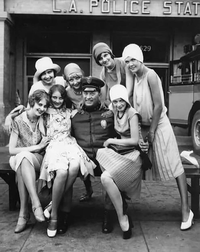 Vintage rare historical photo of a police officer with seven women in 1920s attire outside L.A. Police Station.