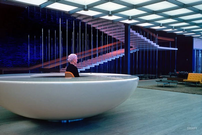 Woman sitting in a large modern bowl-shaped chair in a stylish mid-century interior rare historical photo capturing a unique moment