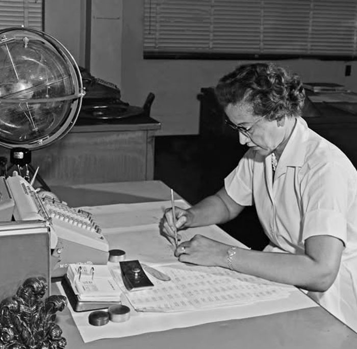 Rare historical photo of a woman working at a desk with documents and a globe in an office setting.