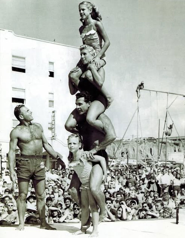 Vintage rare historical photo showing a crowded beach with acrobats performing a human tower stunt.