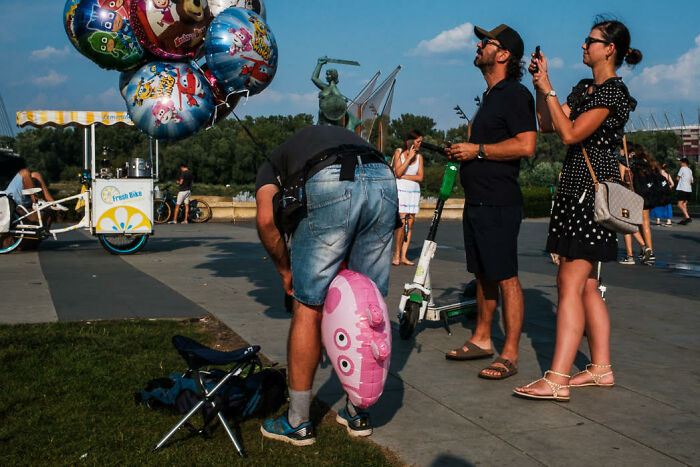 Street photo capturing colorful candid moment with people, balloons, and outdoor urban scene on a sunny day.