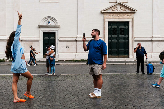 Street photo capturing colorful candid moments of people interacting and taking pictures in an urban setting.
