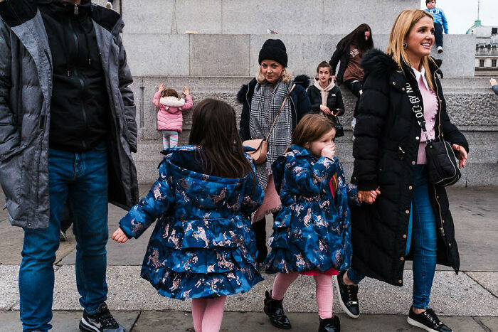 Street photo showing candid moments of people wearing colorful coats, capturing vibrant life in an urban setting.