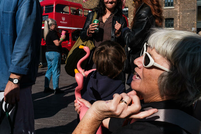 Street photo capturing colorful, candid moments of people interacting outdoors on a sunny day in an urban setting.