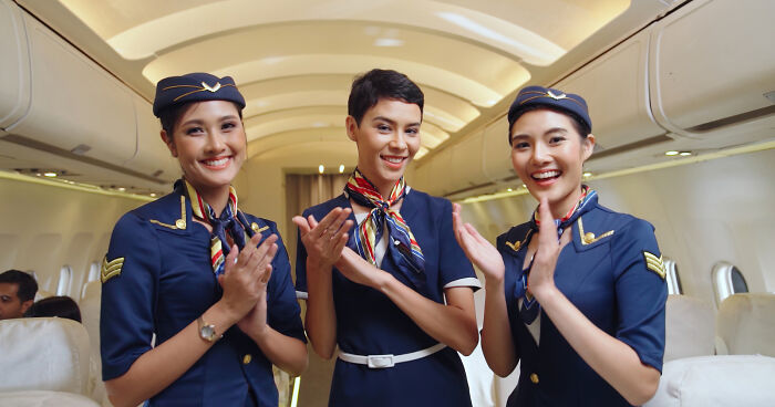 Three flight attendants smiling and clapping inside an airplane cabin for unpopular opinions poll.
