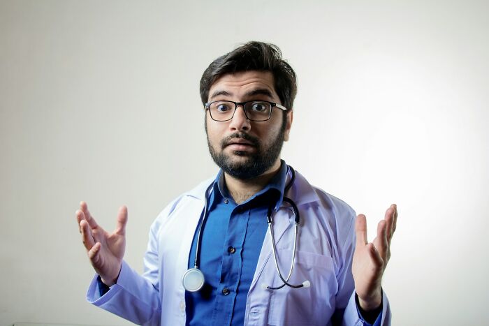 Male doctor with glasses and stethoscope in white coat, expressing surprise about insane hospital experiences.