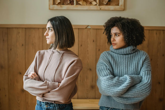 Two women with crossed arms looking away, expressing tension during a vacation without kids babysitting discussion. Two women with crossed arms looking away, expressing tension during a vacation without kids babysitting discussion.