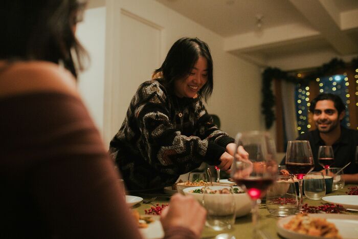 Group of friends enjoying dinner with wine, illustrating foreigners sharing shortcomings of being big in Japan.