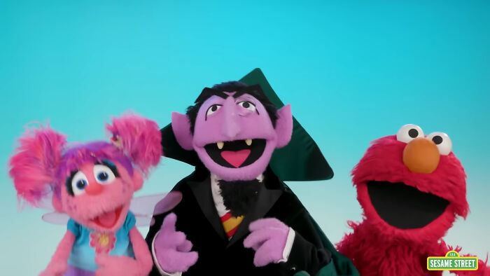 Sesame Street characters including Count von Count with pink and red puppets against a blue background counting countries.