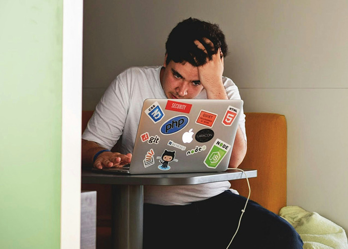 Person working on a laptop covered with tech stickers, representing microfeminism strategies against toxic masculinity.
