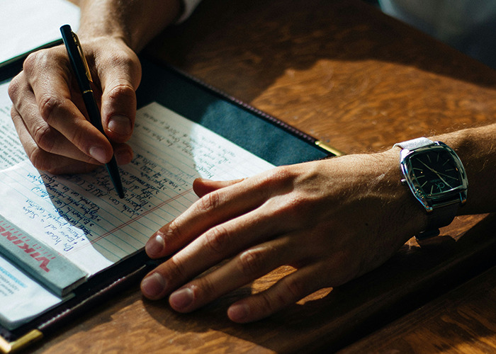 Close-up of a person writing notes by hand on paper, illustrating microfeminism strategies to counter toxic masculinity.