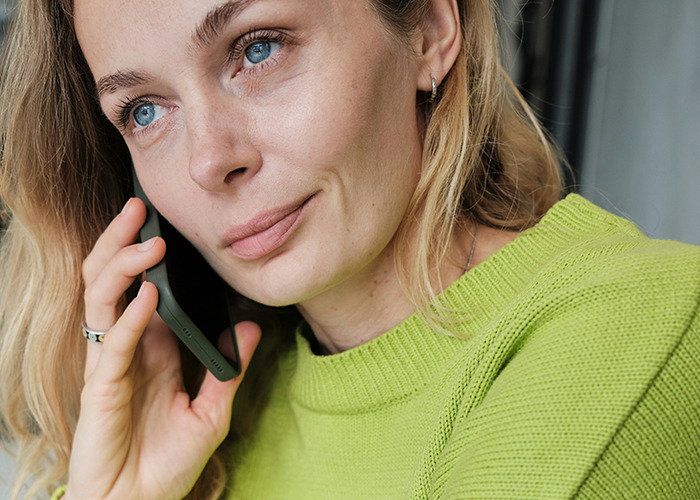 Woman in a green sweater on a phone call, symbolizing microfeminism strategies against toxic masculinity in daily life.