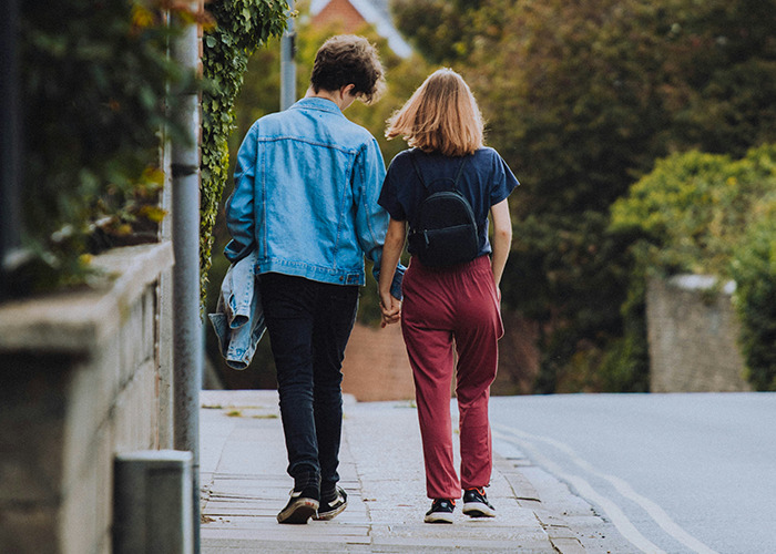 Young couple walking hand in hand on a quiet street, symbolizing microfeminism in countering toxic masculinity.