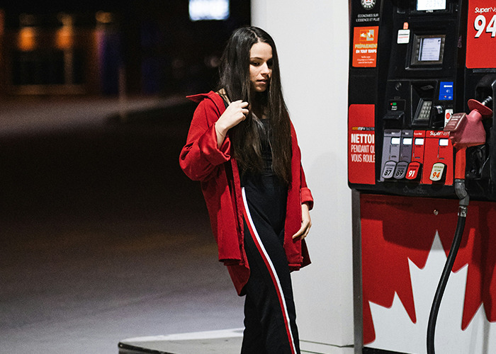 Woman in red jacket standing at gas station at night illustrating microfeminism countering toxic masculinity concept