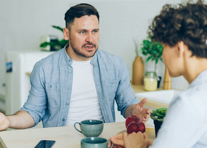 Two people having a serious conversation at a table, illustrating microfeminism challenging toxic masculinity.