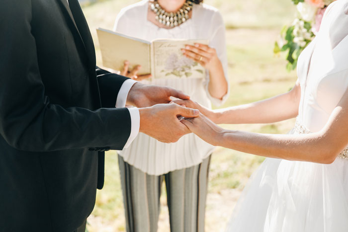 Couple holding hands during wedding ceremony with guests shocked and confused after eloping three years earlier. Couple holding hands during wedding ceremony with guests shocked and confused after eloping three years earlier.