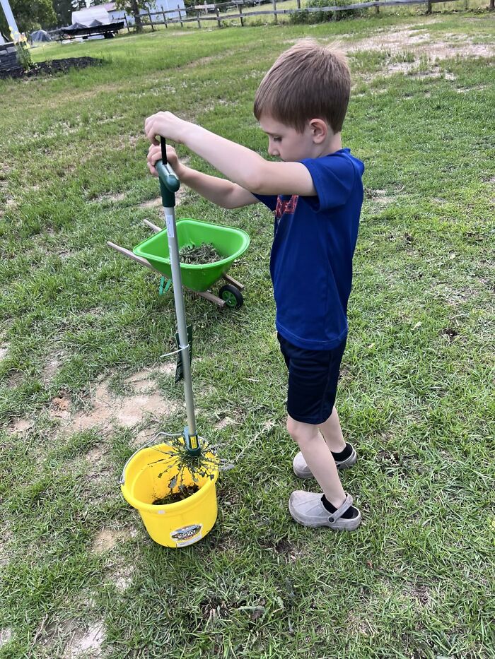 Child using gardening tools outdoors with a wheelbarrow and bucket, showcasing gardening tools and decor for an outdoor oasis.