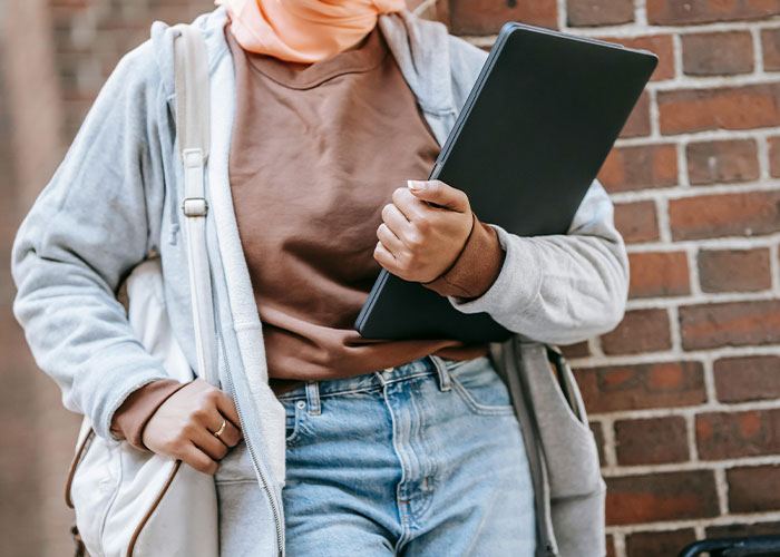 Person holding laptop and bag walking by brick wall, illustrating security footage of weirdest and scariest random things caught on tape
