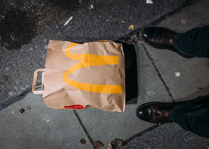 Brown McDonald's paper bag on the ground next to a person's feet, capturing weirdest and scariest random moments on security tape.