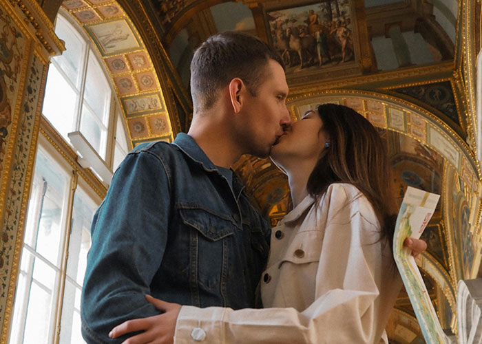 Couple sharing a kiss inside an ornate building, captured with security tape style emphasizing weird and random moments.