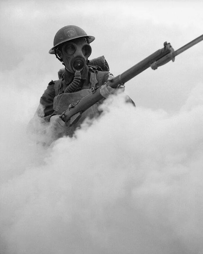 Soldier wearing a gas mask and helmet holding a rifle surrounded by smoke illustrating weird things about history.