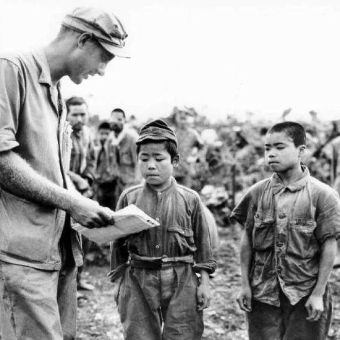 Black and white photo showing a soldier interacting with two children, illustrating weird things about history and historical moments.