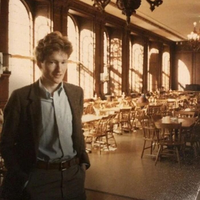 Young man standing in a sunlit vintage dining hall, representing learning weird things about history on Instagram.